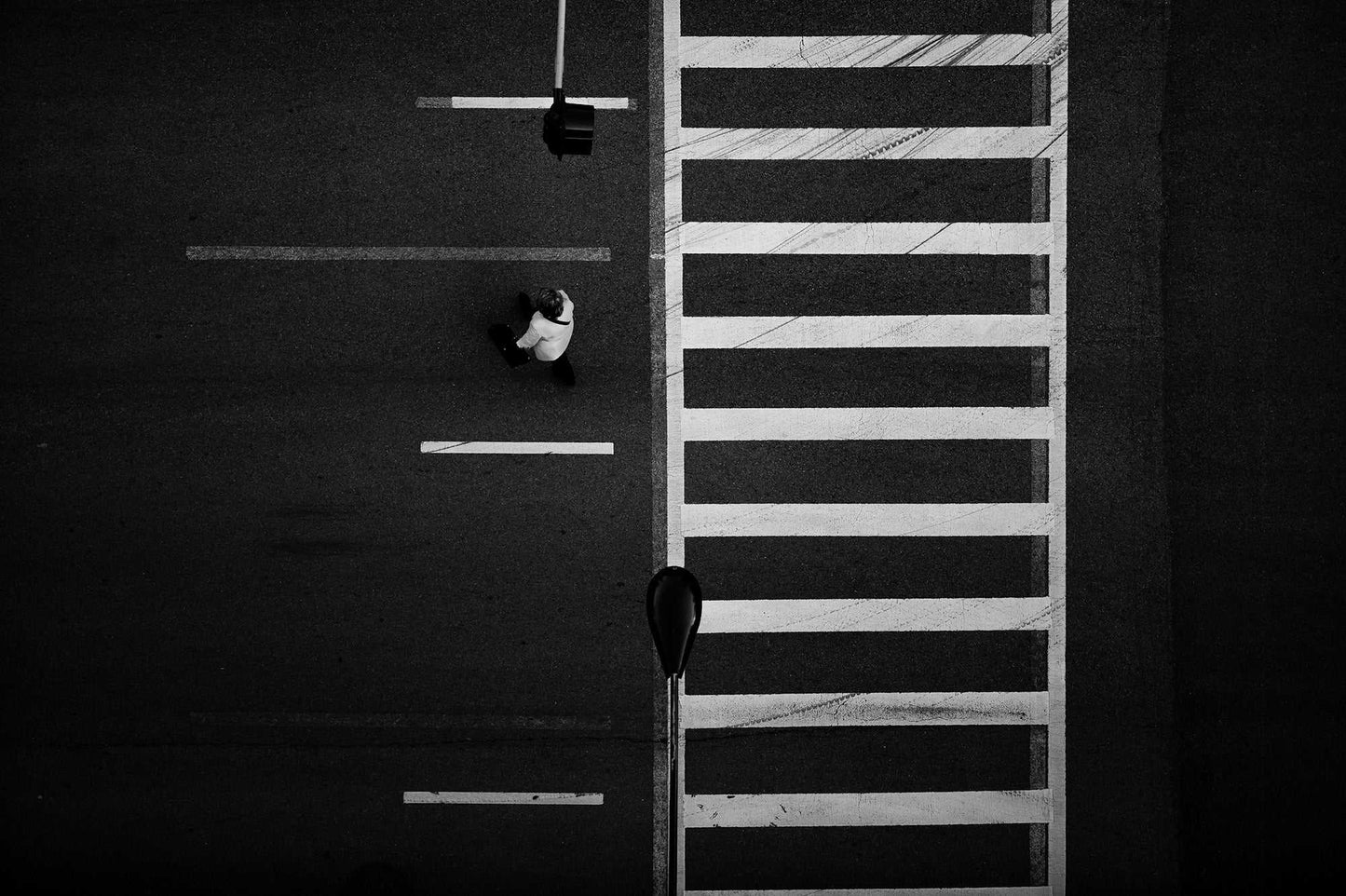 Overhead black and white photograph of Chicago crosswalk with pedestrian and graphic street pattern