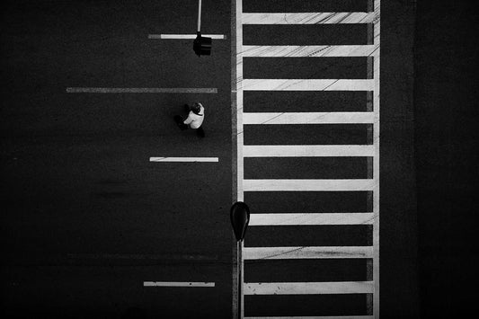 Overhead black and white photograph of Chicago crosswalk with pedestrian and graphic street pattern