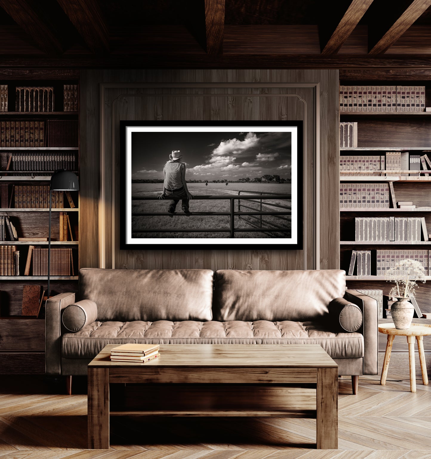 Framed black and white image of a woman on a ranch fence with riders approaching, on the wall of warm wood living area.