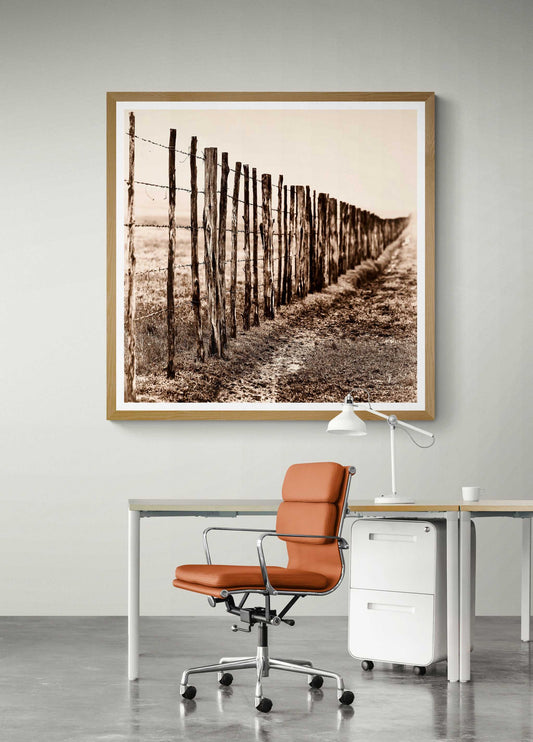 Framed Eight Miles from Nowhere: Fence Line in the Fog, 44 Farms artwork displayed above a modern desk setup. Ideal for rustic office decor.
