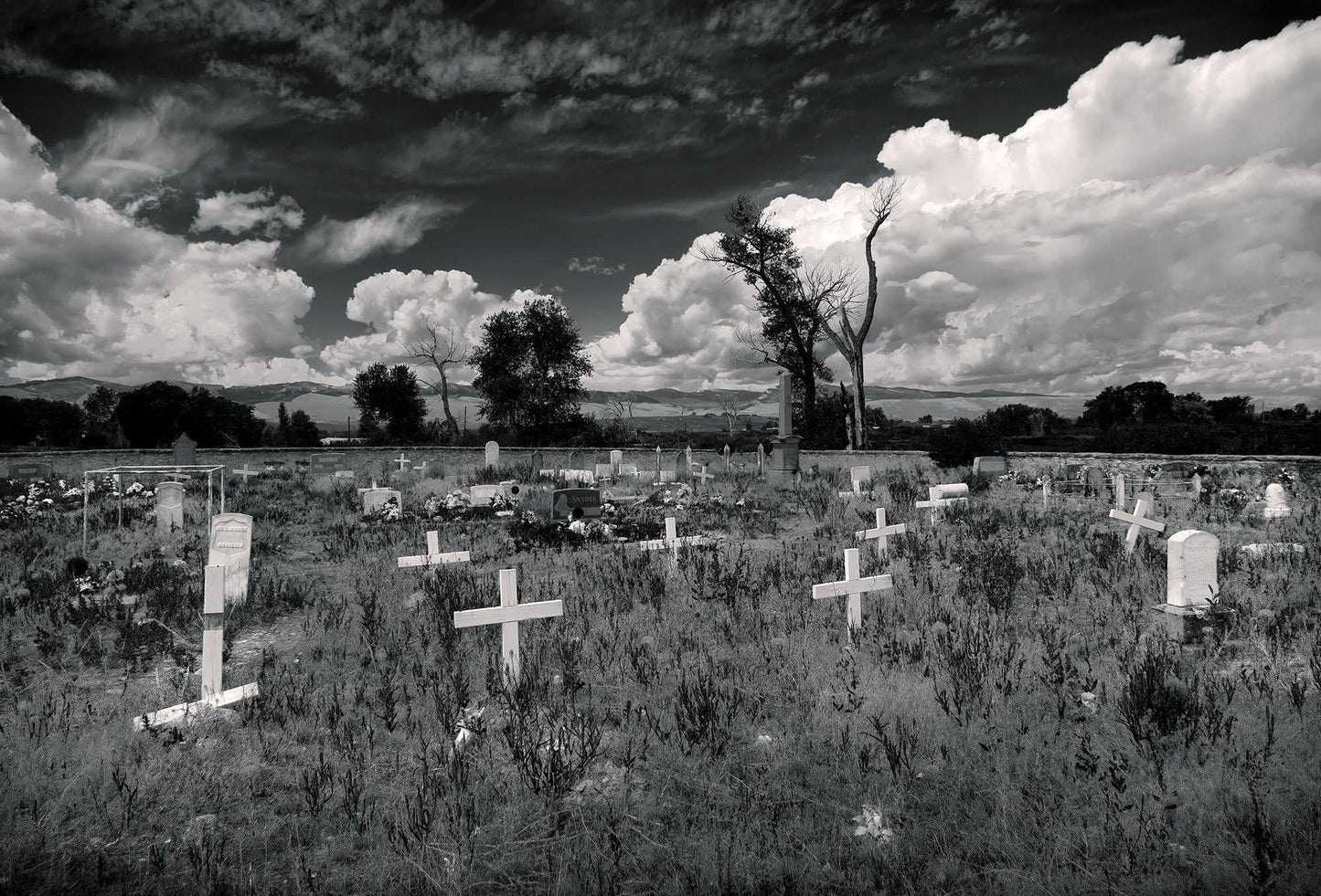 Fort Washakie Cemetery — black and white photograph of burial grounds on the Wind River Reservation in Wyoming beneath expansive clouds, a quiet study of place, history, and landscape