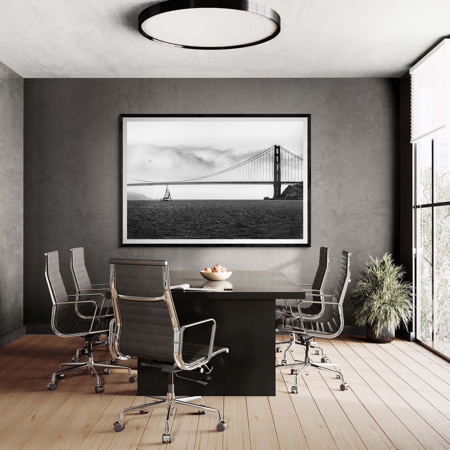 Black framed fine art print of a sailboat under The Golden Gate Bridge on the wall of a contemporary boardroom with windows.