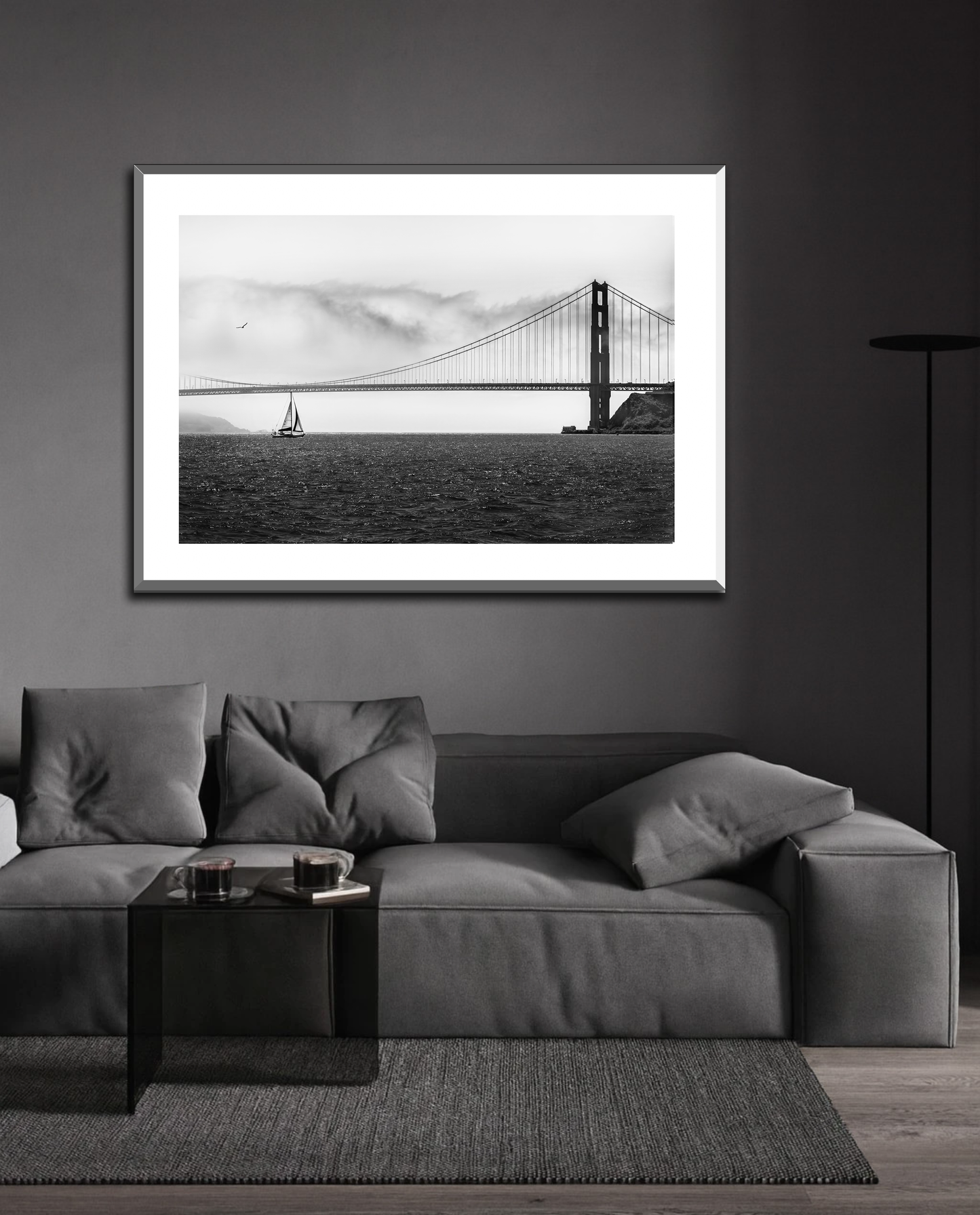 Framed black and white print of sailboat in front of The Golden Gate Bridge in a grey, minimalist modern living room.