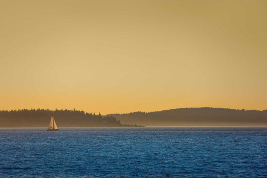 Golden Hour Sailboat — fine art photograph of a sailboat on Puget Sound at sunset with warm golden sky and deep blue water near Seattle