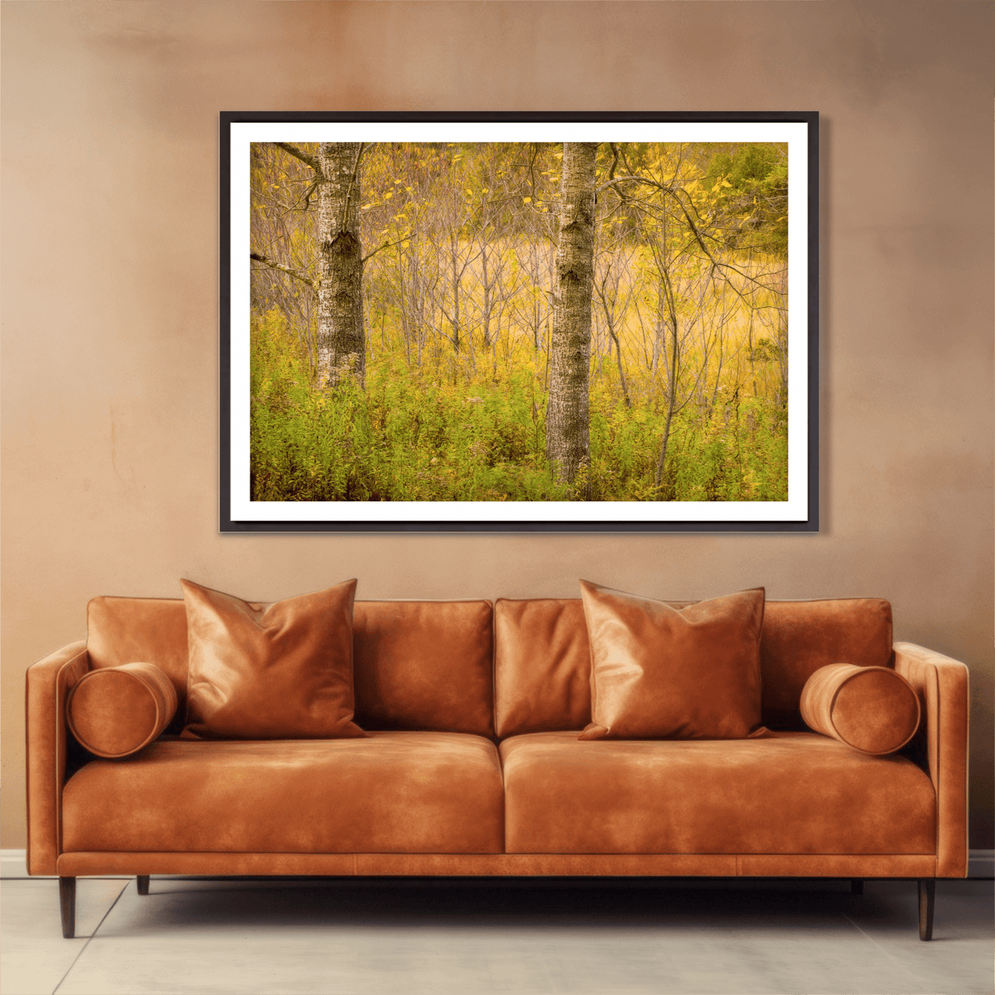 Golden Woods autumn forest photograph framed above a leather sofa, enhancing interior decor with warm fall colors and serene woodland composition.