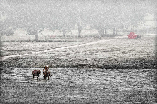 Cowboy leading a saddled horse through a snowy Texas pasture, evoking a quiet winter scene titled Home for Christmas.