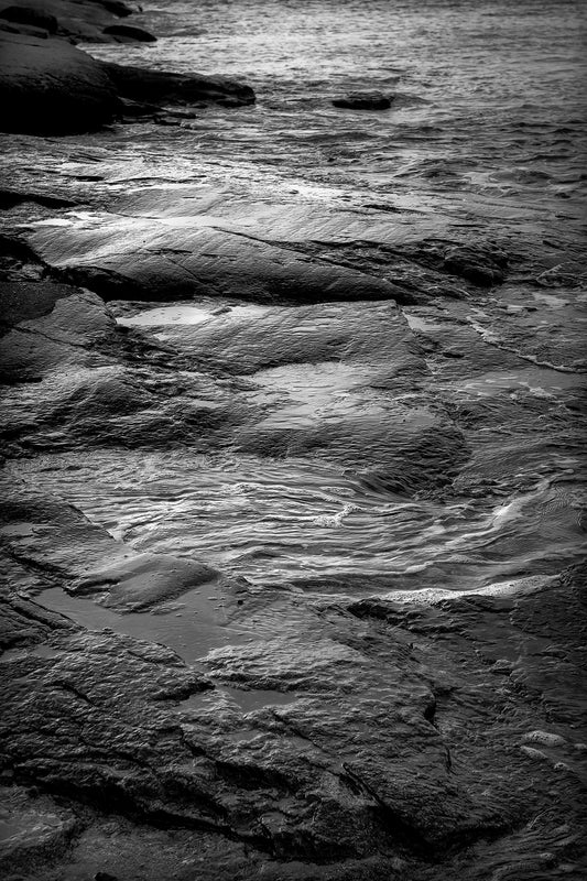 Black and white coastal detail of tidal water flowing over granite rocks at Cushing Maine with textured shoreline and soft tonal contrast