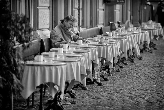 Solitary man seated at an outdoor café in Zurich, Switzerland, captured in black and white with strong perspective and repetition