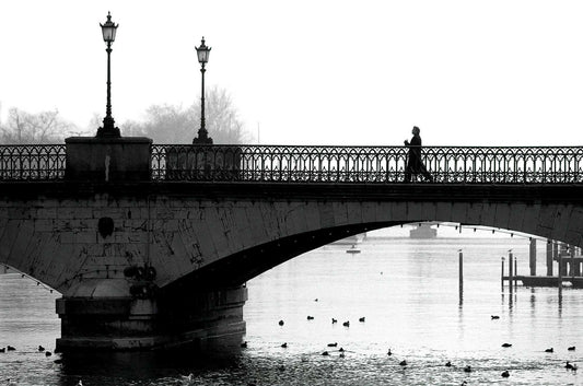 Man walking across a fog-covered bridge over the River Limmat in Zurich, Switzerland in a minimalist black and white composition
