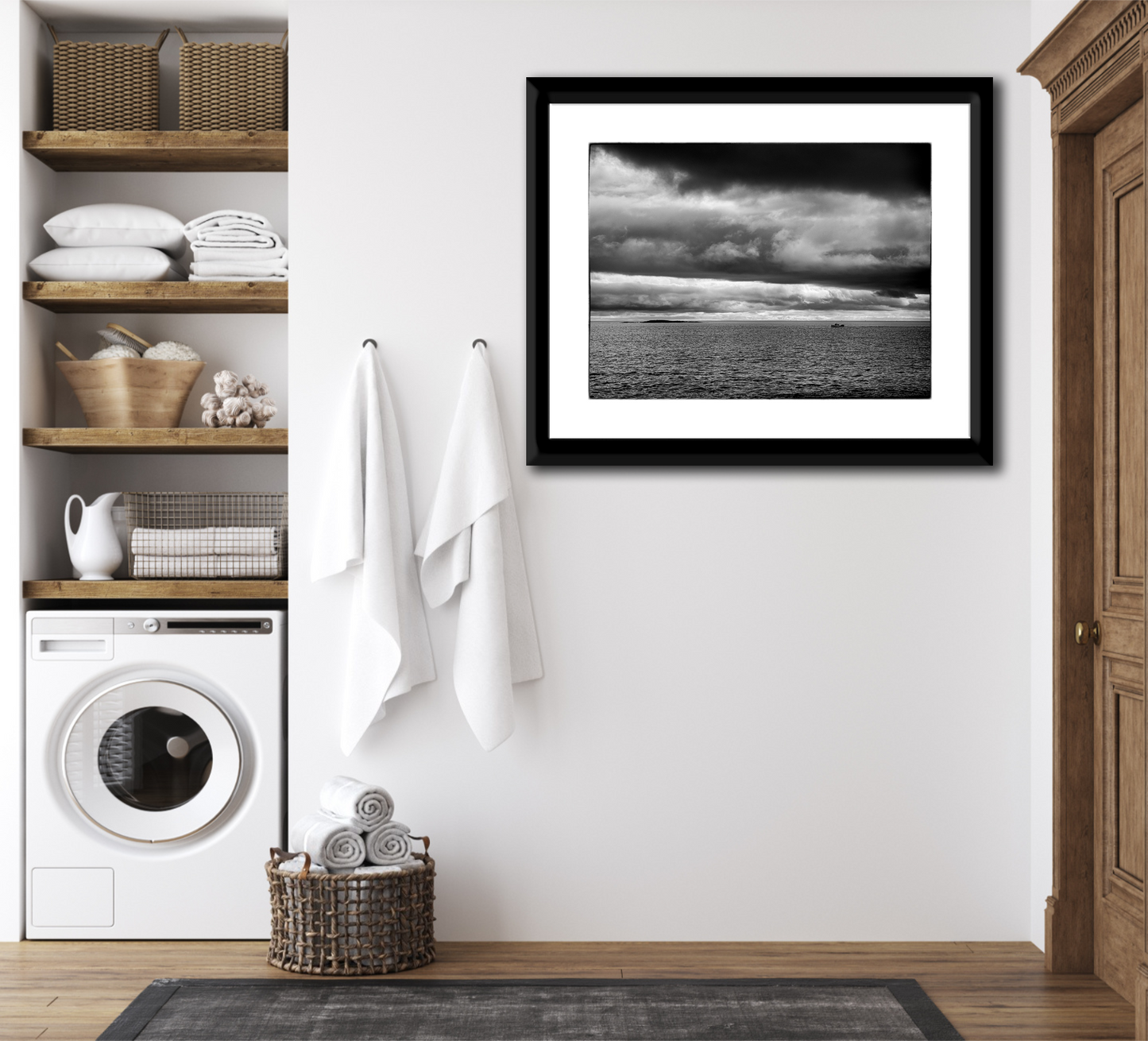 Framed black and white seascape photograph of the Atlantic Ocean at Marshall Point, Maine displayed in a laundry room interior