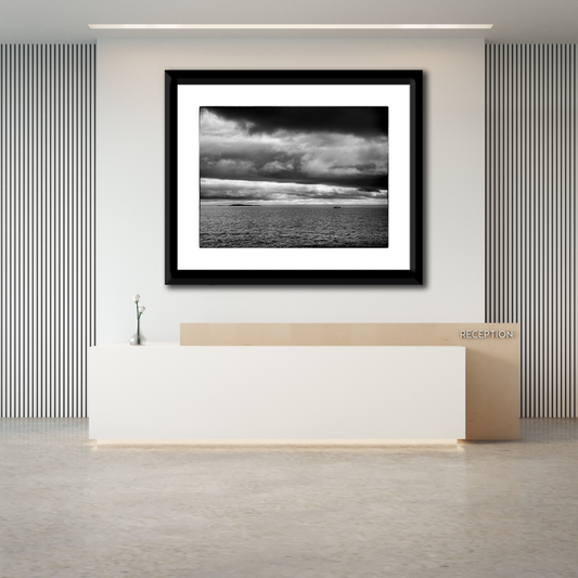 Framed black and white seascape photograph of the Atlantic Ocean at Marshall Point, Maine displayed above a modern office reception desk