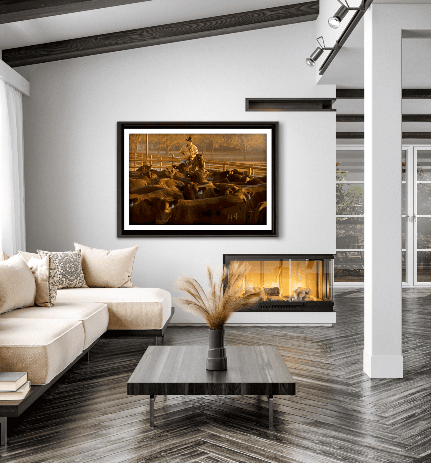 Golden hour cowboy and cattle artwork titled Morning Roundup at 44 Farms by Michael Hart showcased in a bright, contemporary living room with fireplace.