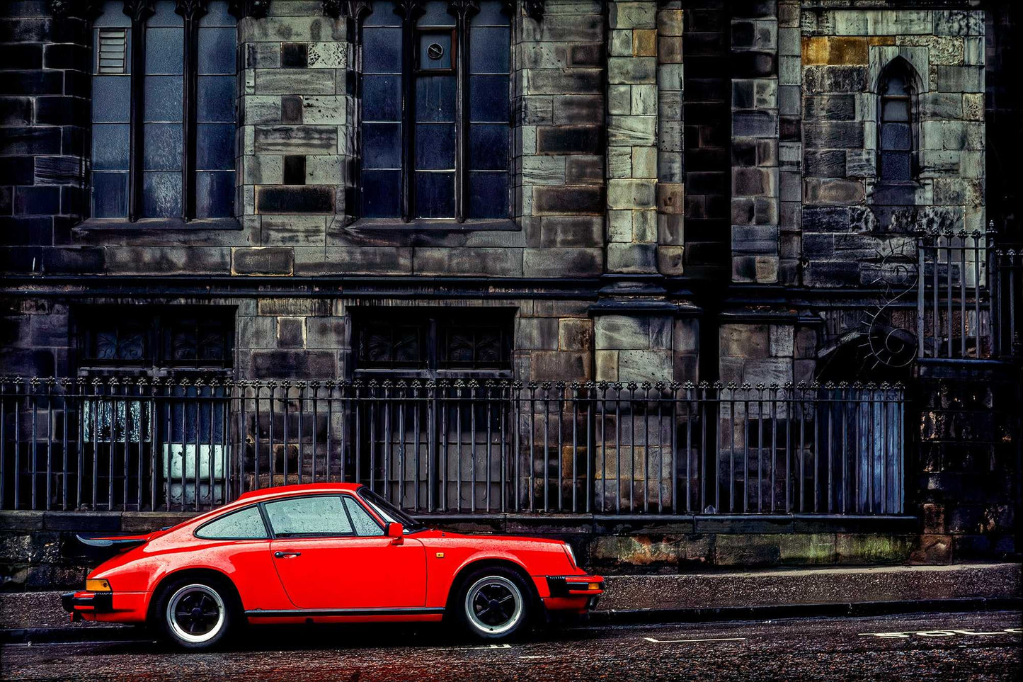 Red Porsche parked beside St. Giles’ Cathedral in Edinburgh—Kodachrome street photograph contrasting modern car with historic Gothic architecture.