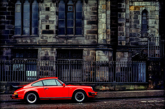 Red Porsche parked beside St. Giles’ Cathedral in Edinburgh—Kodachrome street photograph contrasting modern car with historic Gothic architecture.