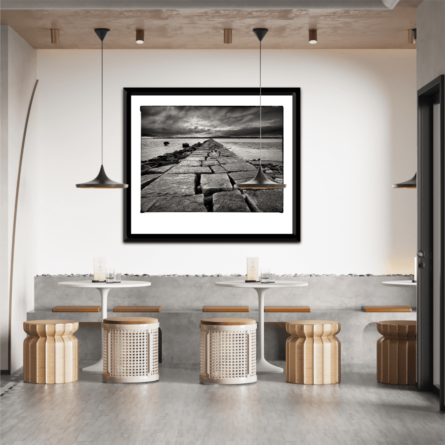 Breakwater, Rockland ME – Award-Winning Black & White iPhone Photo, Limited Edition Print displayed in a modern cafe with minimalist decor. Dramatic seascape adds moody elegance to interior design.