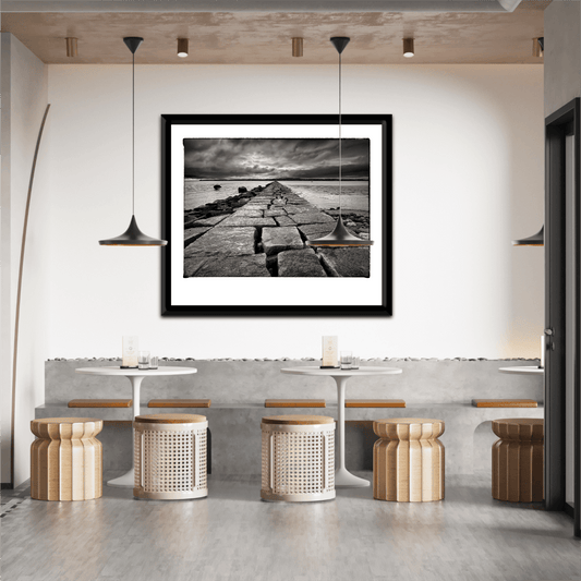 Breakwater, Rockland ME – Award-Winning Black & White iPhone Photo, Limited Edition Print displayed in a modern cafe with minimalist decor. Dramatic seascape adds moody elegance to interior design.
