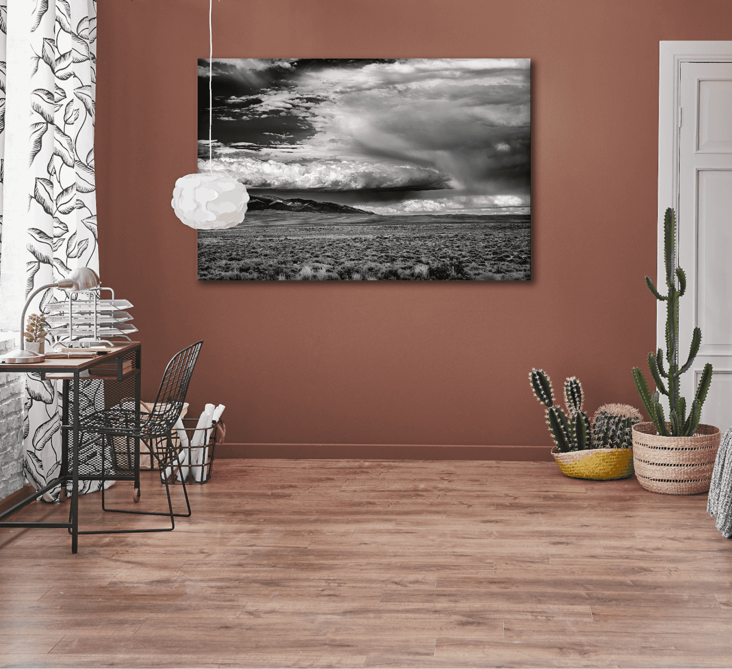 A black and white framed image of summer storm clouds over eastern Wyoming shown unframed on the wall in a warm toned room setting