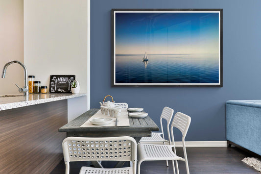 Limited edition coastal print of a sailboat on Galveston Bay displayed in a modern dining area, enhancing nautical interior design with tranquil tones.