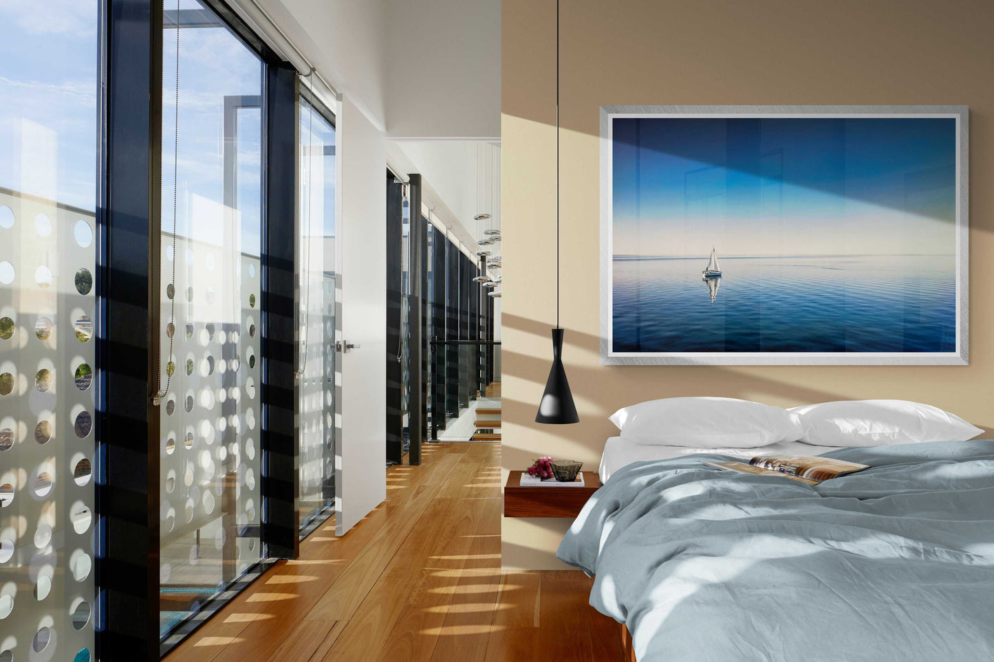 Coastal sailboat wall art titled The Calm enhances a modern bedroom with soft lighting and nautical tones, perfect for serene interior design themes.