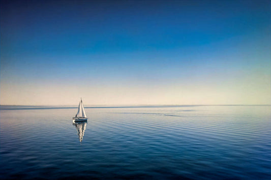 Minimalist sailboat on calm water in Galveston Bay with mirror reflection and seamless blue sky