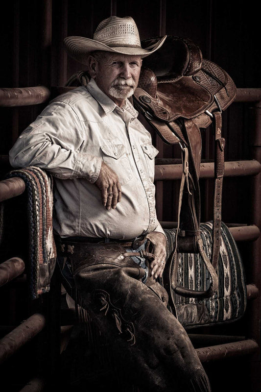 Portrait of a Texas ranch foreman in cowboy hat beside saddle at 44 Farms, showing experience, authority, and Western ranch life.