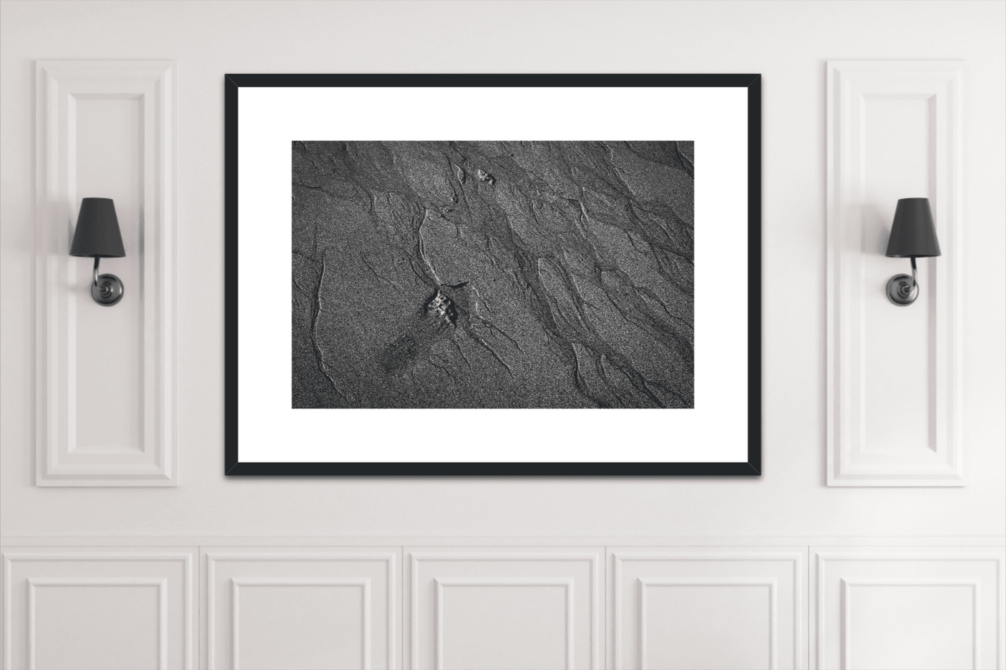 Traces #2 framed black and white sand pattern print mounted between wall sconces. Sophisticated artwork for classic white-paneled interiors.