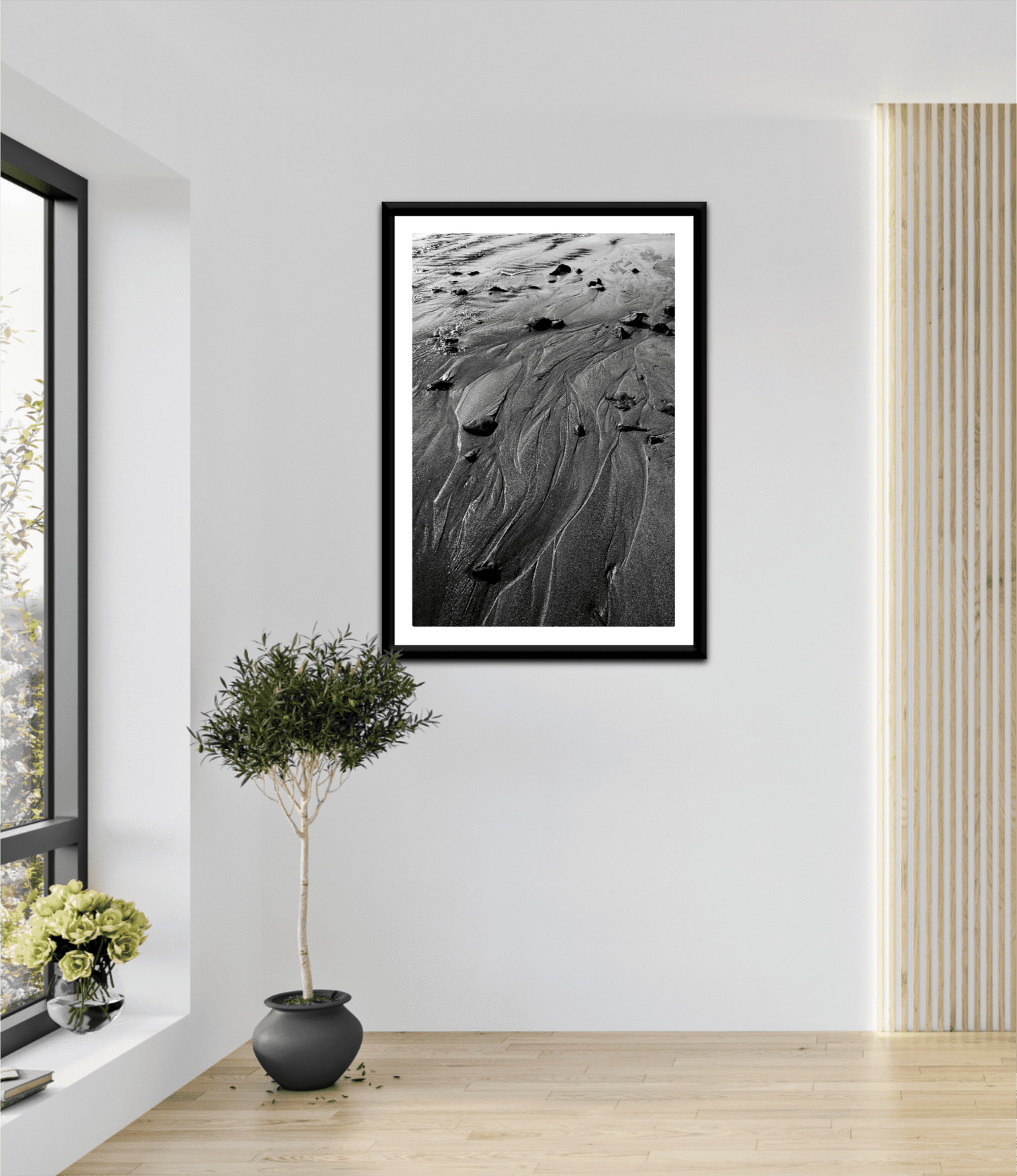 Framed 'Traces #3' black and white sand artwork displayed in a bright, modern room with natural light and minimalist decor elements.