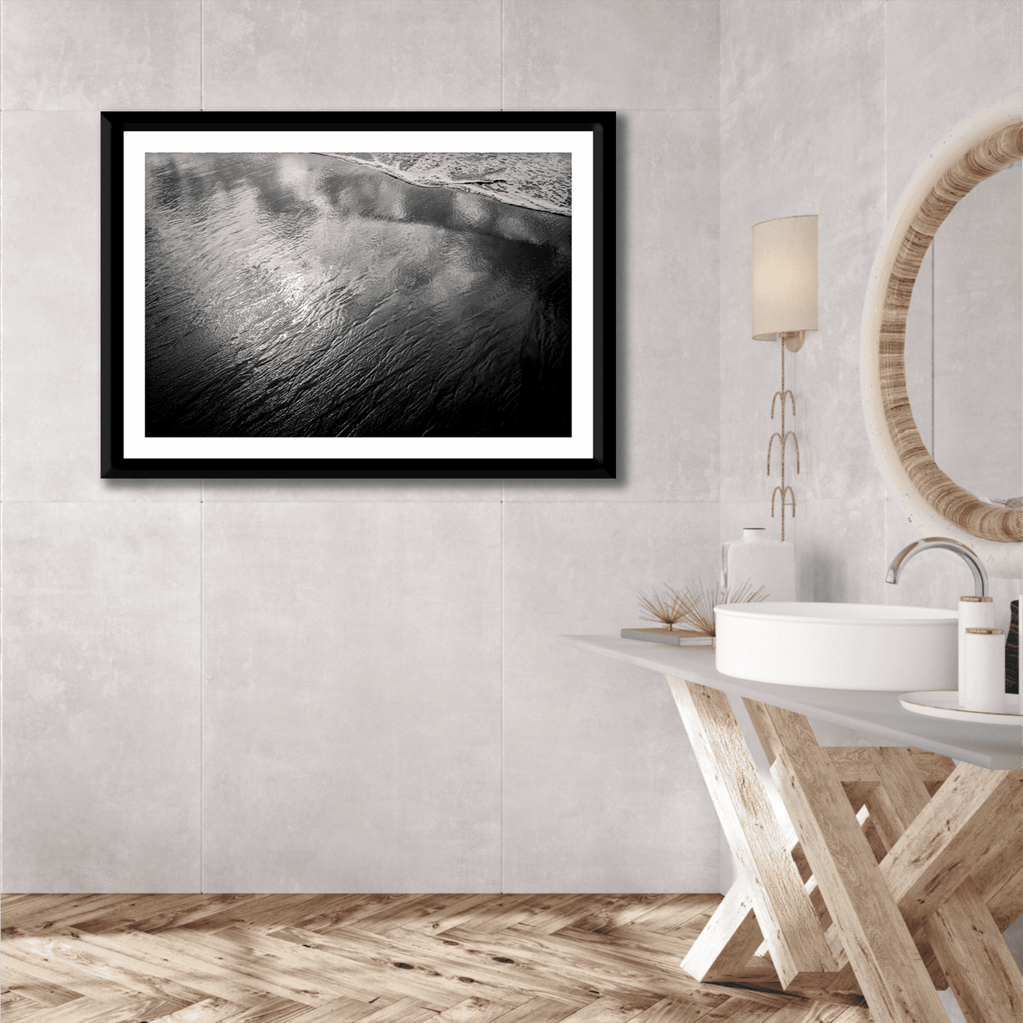 Elegant bathroom interior with framed black and white print 'Traces #4 – Reflections at the Sea Edge, Maine' above modern vanity and round mirror.