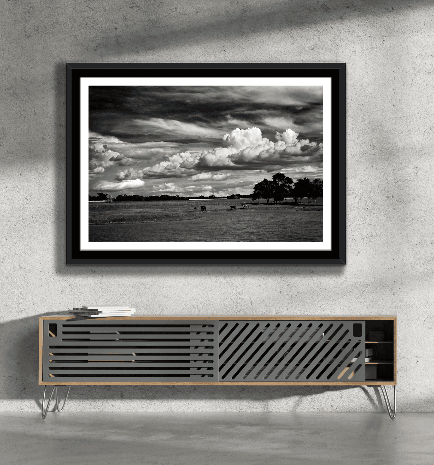 Texas ranch life artwork 'Under a Texas Sky' in black and white, framed above a minimalist console in a concrete wall living space.