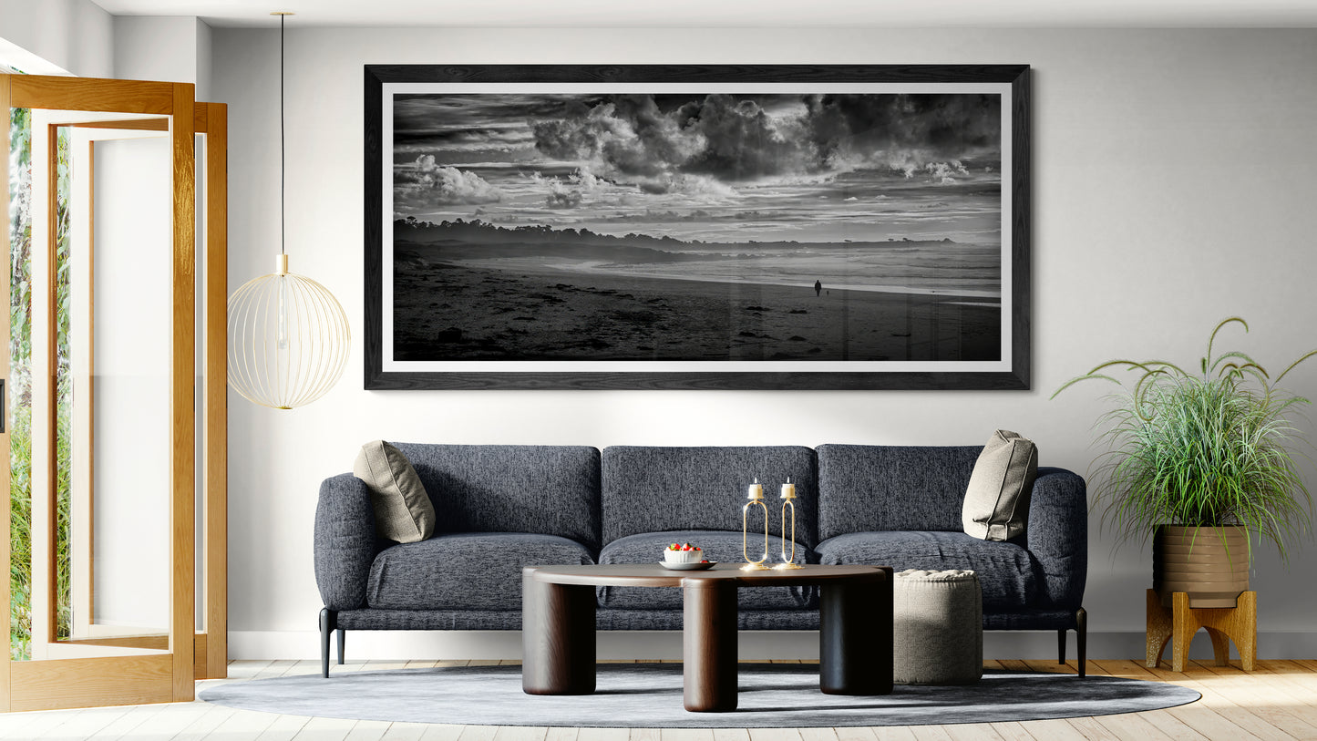 Black and white panoramic coastal photograph displayed as wall art above a sofa in a contemporary living room