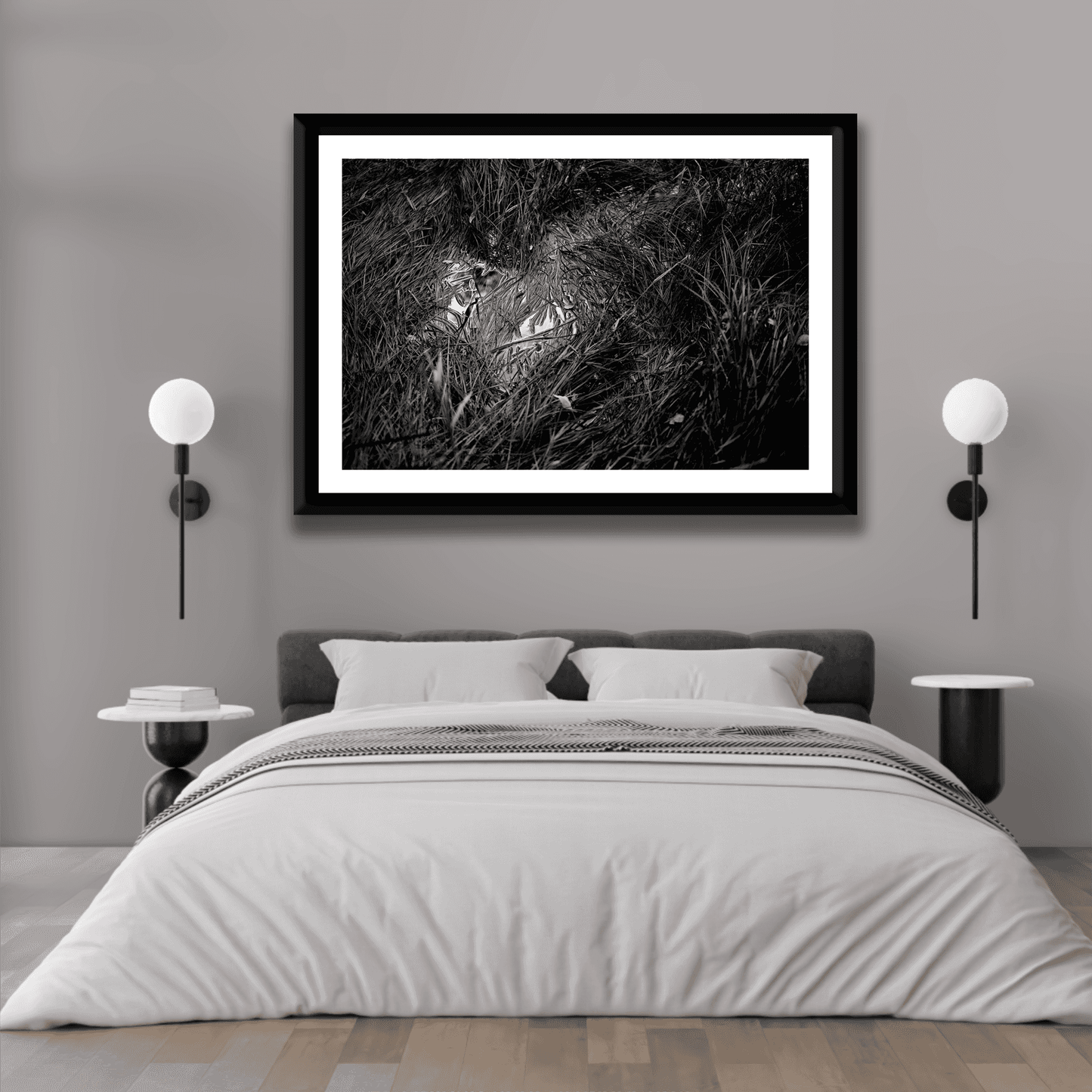 Monochrome print 'Water & Reeds – A Scene in Acadia National Park in Black and White' featured above a bed in a minimalist gray bedroom.