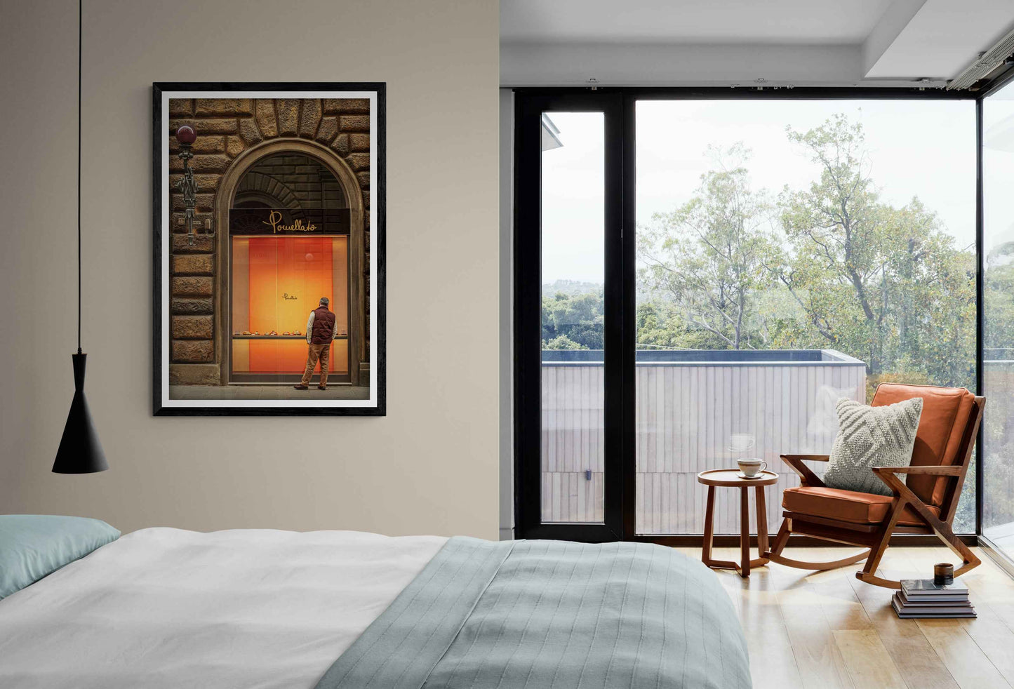Fine art photo of man shopping in Florence on the wall of a modern bedroom with large window, orange armchair, and framed street scene art