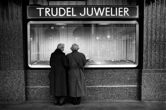 Two women viewing a jewelry display window in Zurich, Switzerland, captured in black and white with reflection and street detail