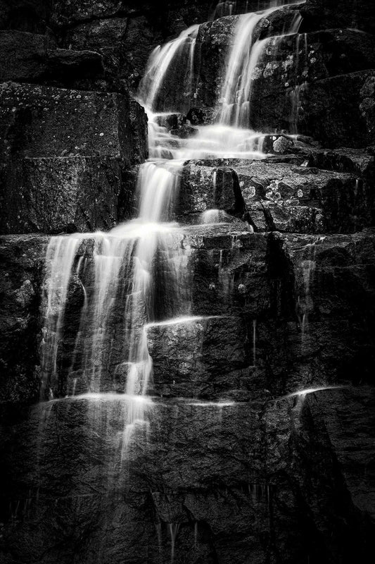 Black and white waterfall photograph of cascading water over rugged rock formations in Acadia National Park, Maine.