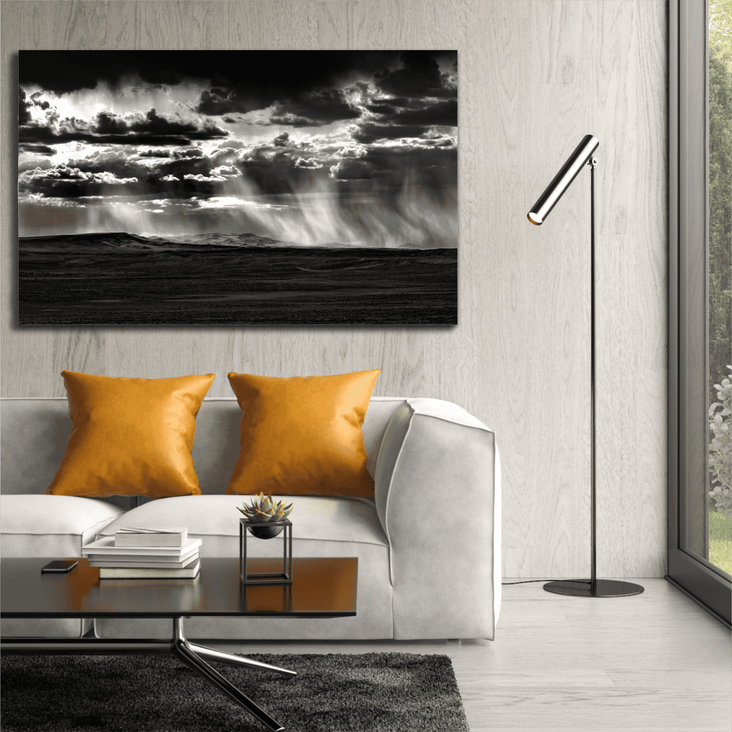 Black and white Wyoming Rainstorm fine art print by Michael Hart displayed above a modern white sofa with orange pillows in a contemporary living room.