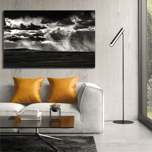 Black and white Wyoming Rainstorm fine art print by Michael Hart displayed above a modern white sofa with orange pillows in a contemporary living room.
