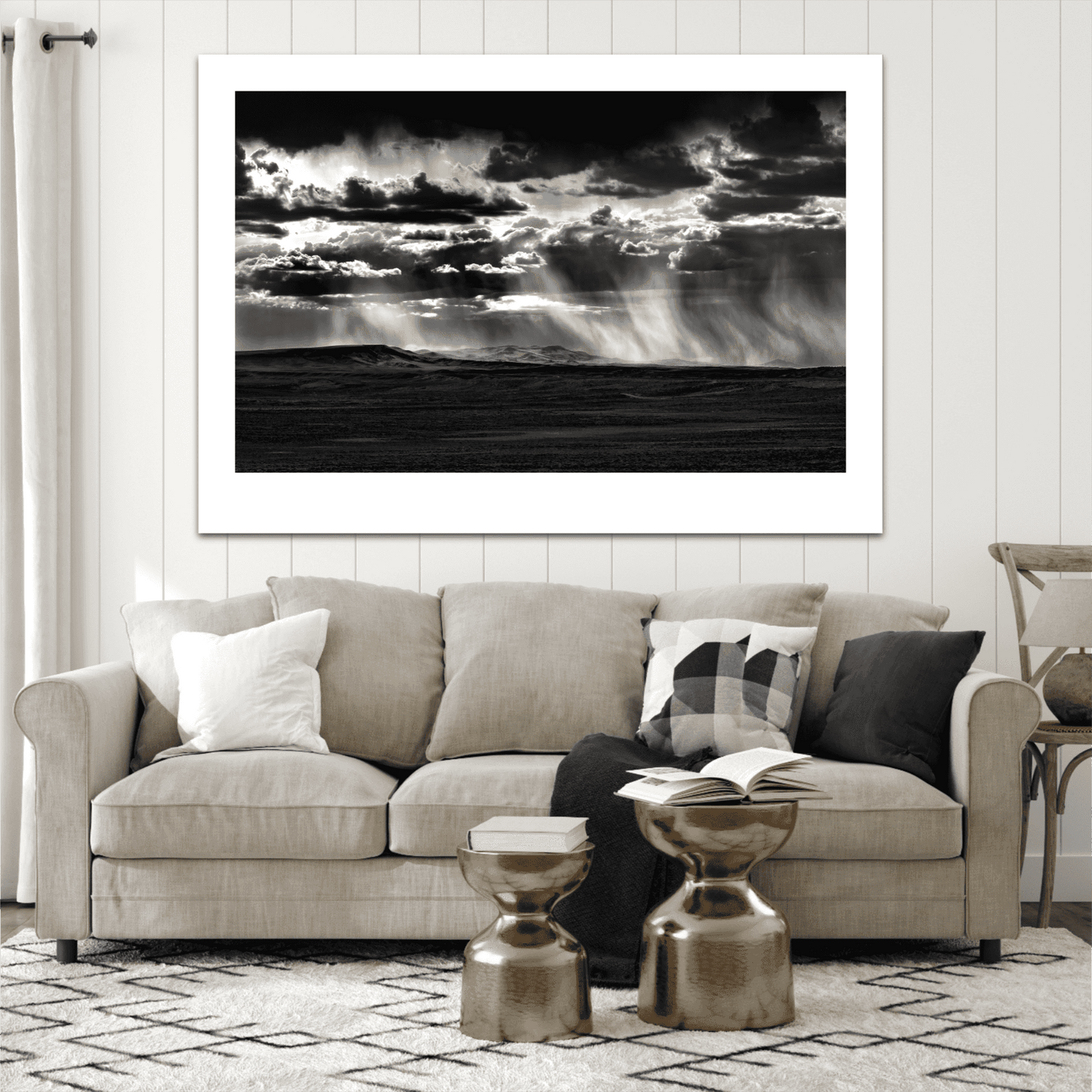 Unframed "Wyoming Rainstorm – Backlit Virga Over the Plains"  print in black and white mounted above a beige couch in a cozy, modern farmhouse-style living room.